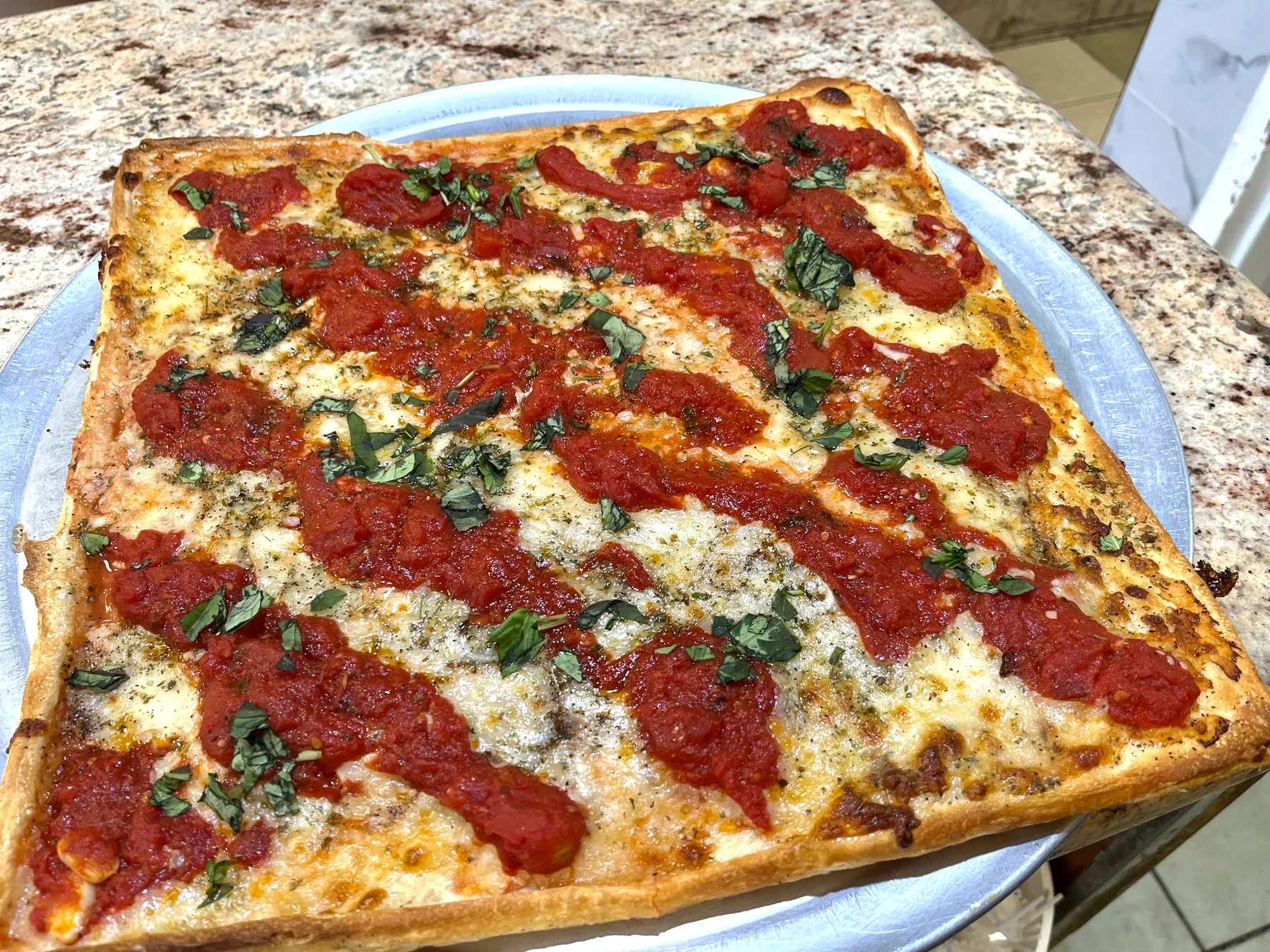 Grandma pizza with tomato sauce and basil