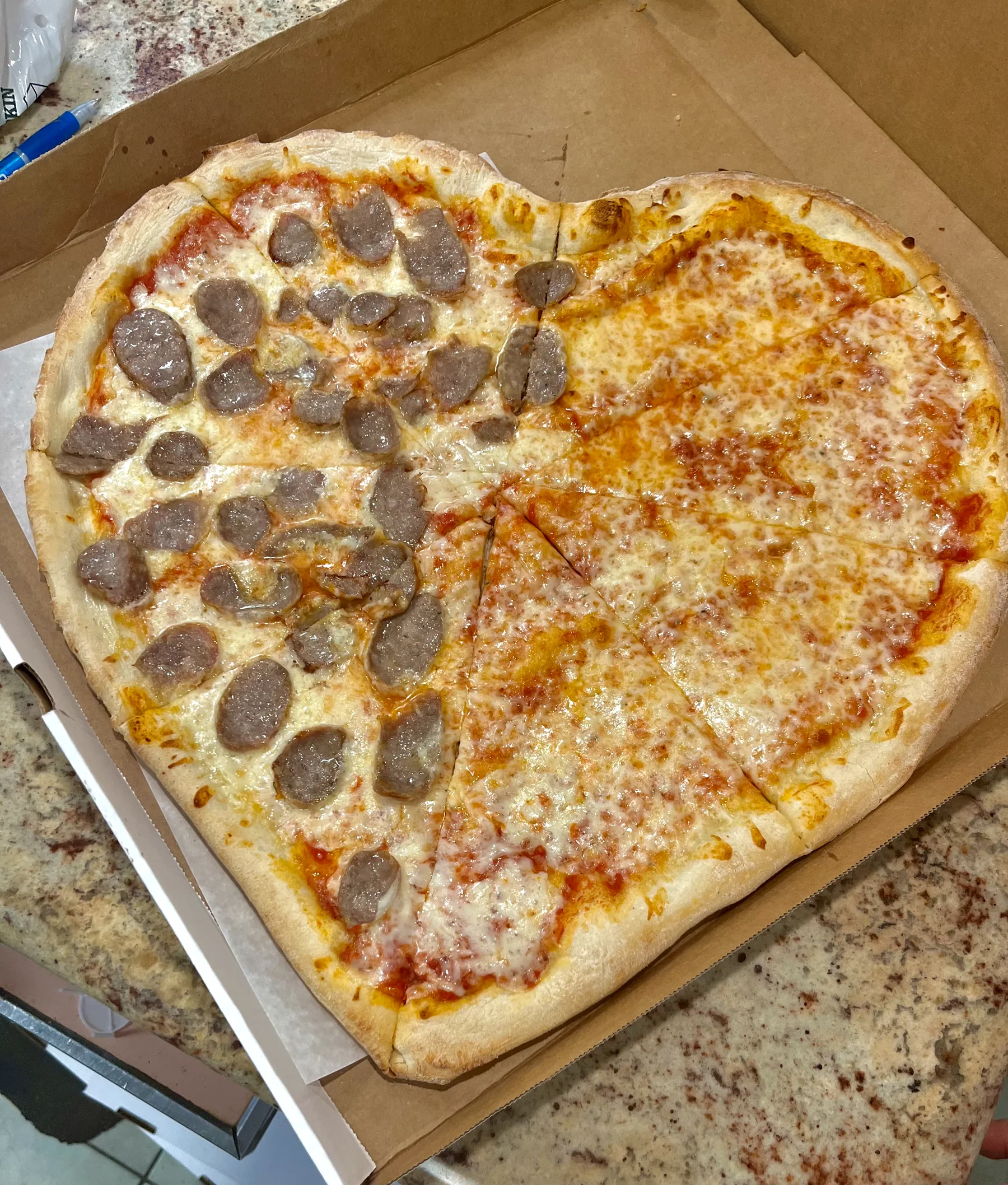 A heart-shaped cheese and sausage pizza
